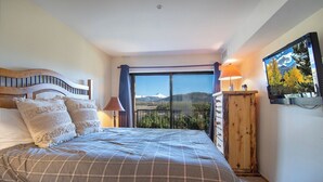 Ein Schlafzimmer mit einem großen Bett, einem Holzkopfstück, einem Schminktisch und einem Fernseher an der Wand.