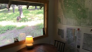 A wooden table with a lamp, a chair, and a window overlooking a grassy area with trees. - SWAN VALLEY BUNKBED EFFICIENCY IN CONDON (Condon)