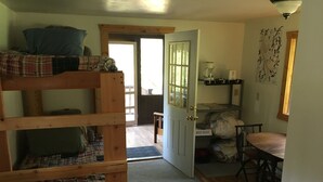 A cozy room with a bunk bed, a small table with chairs, a door leading to another room, and a wall-mounted shelf with a coffee maker. - SWAN VALLEY BUNKBED EFFICIENCY IN CONDON (Condon)