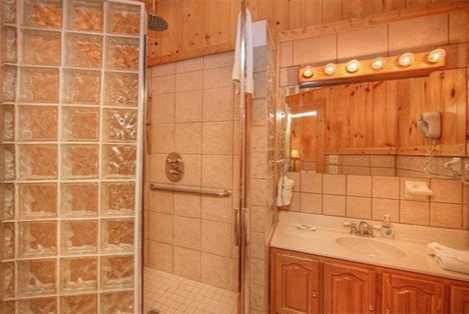 Un baño con cabina de ducha de vidrio, armarios de madera, tocador con espejo y un perchero para toallas.