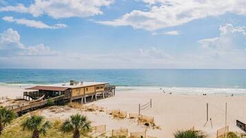 A beachside building with a wooden deck and a view of the ocean.