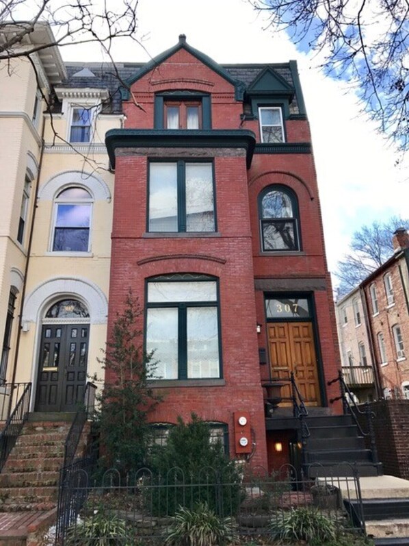 A two-story red brick building with a central entrance, large windows, and a small porch area. - Location, Convenience and Charm by Capitol Hill FREE Parking Included (Washington)