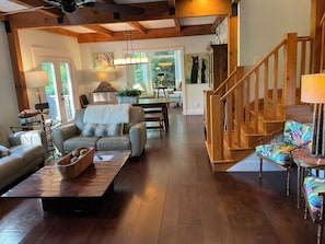 A spacious living room with a wooden staircase, a dining area, and a view of the outdoors. - Freshly Decorated, 1.5 miles to downtown Highlands w/ views of Mount Satulah! (Highlands)