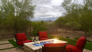 An outdoor patio with a stone fire pit, red chairs, and a table with a bottle and glass. - Casita Del sol, 1 BR 1BA-Sleeps 2. Minimum Stay 4 nights. Great North Phoenix (Phoenix)