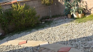 A gravel driveway leading to a house with a brick pathway and a small red brick step.