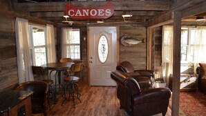 A wooden interior with a dining area, leather sofas, and a sign reading "CANOES".