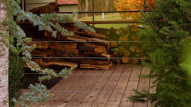 A wooden deck with a view of autumn foliage and a building in the background.