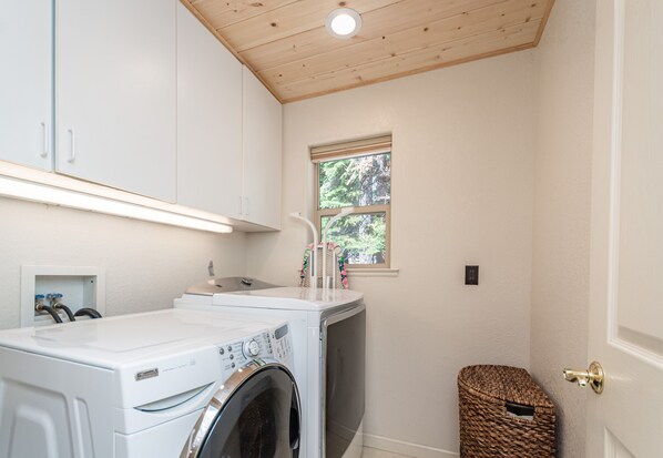 A laundry room with a washing machine, a dryer, and a small window.