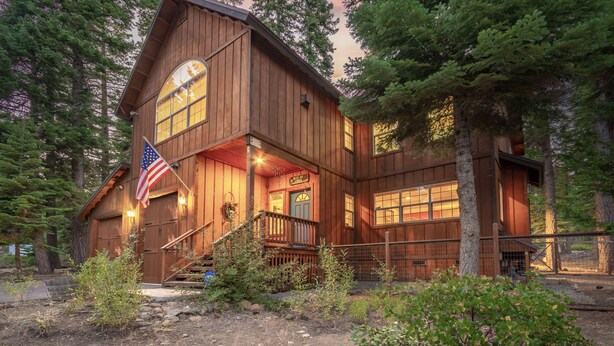 A wooden cabin with a porch, an American flag, and a sign that reads "Welcome". - Charming Dog-Friendly Lake Tahoe Cabin – Hot Tub, Pool Table & Walk to Beach (Carnelian Bay)