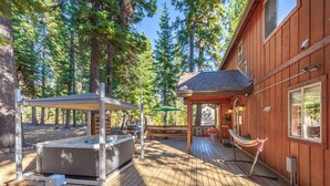 A wooden cabin with a hot tub, outdoor seating, and a hammock. - Charming Dog-Friendly Lake Tahoe Cabin – Hot Tub, Pool Table & Walk to Beach (Carnelian Bay)