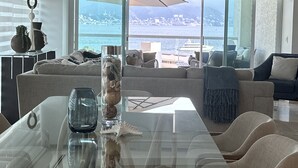 Un salon moderne avec une table à manger en verre, des canapés et une vue sur la mer.