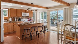A kitchen with wooden cabinets, a microwave, and a large island with bar stools. - Anderson Island Luxury Beach Home. Kayak, HotTub, Paddle Board, Beachfront, View (Anderson Island)