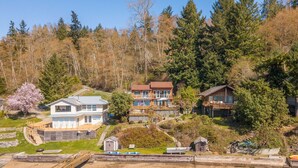 A residential area with houses, a dock, and a small shed. - Anderson Island Luxury Beach Home. Kayak, HotTub, Paddle Board, Beachfront, View (Anderson Island)