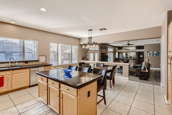 A spacious kitchen with a central island, a dining area with chairs, and a bar area.
