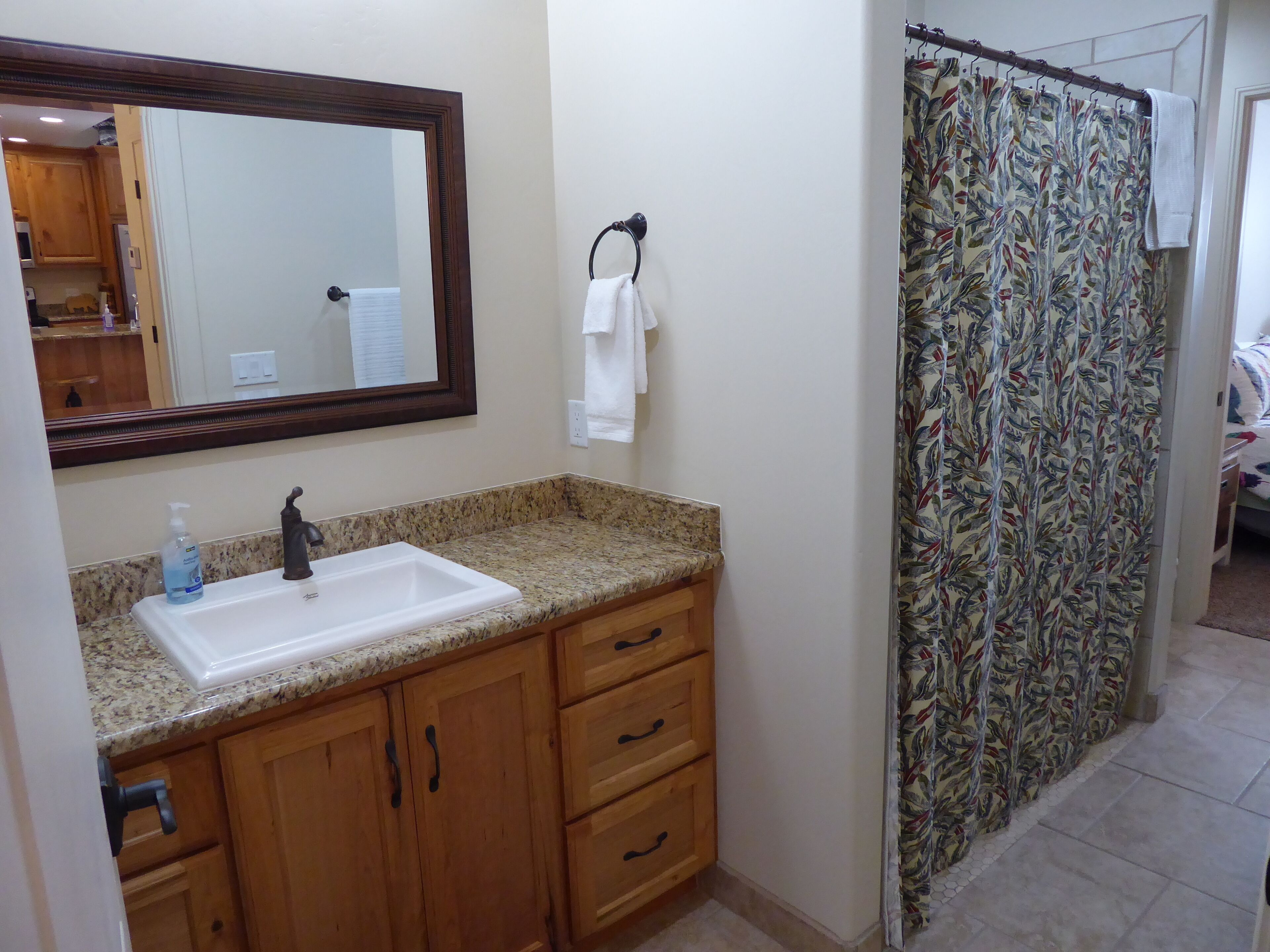A bathroom with a sink, mirror, wooden cabinets, and a shower curtain.
