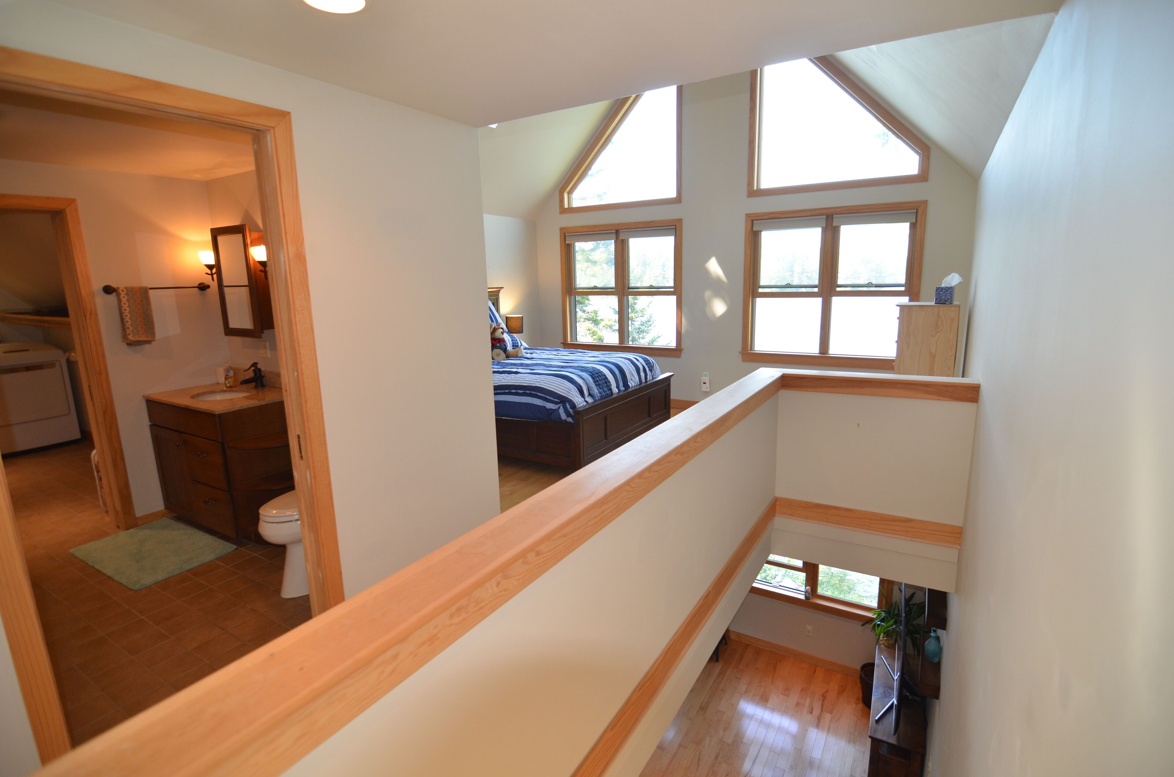 A bedroom with a large window, a wooden ceiling, and a view of the outdoors.