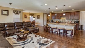 A spacious living room with a leather sofa, a coffee table, and a patterned rug. - Charming 6-BR Home with Open Space & Park, Ideal for Gatherings (Parker)