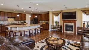 A spacious living room with a fireplace, a large TV, and leather sofas. - Charming 6-BR Home with Open Space & Park, Ideal for Gatherings (Parker)