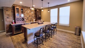 A modern kitchen with a central island, bar stools, and pendant lighting. - Charming 6-BR Home with Open Space & Park, Ideal for Gatherings (Parker)