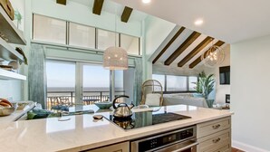 A modern kitchen with a large island, built-in oven, and pendant lighting.