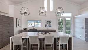 A spacious kitchen with a large island, pendant lights, and a view of the outdoors.