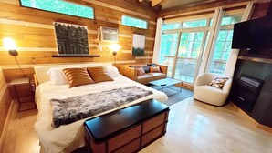 Camera da letto in stile chalet moderno con un letto grande, una poltrona, una sedia e un camino.