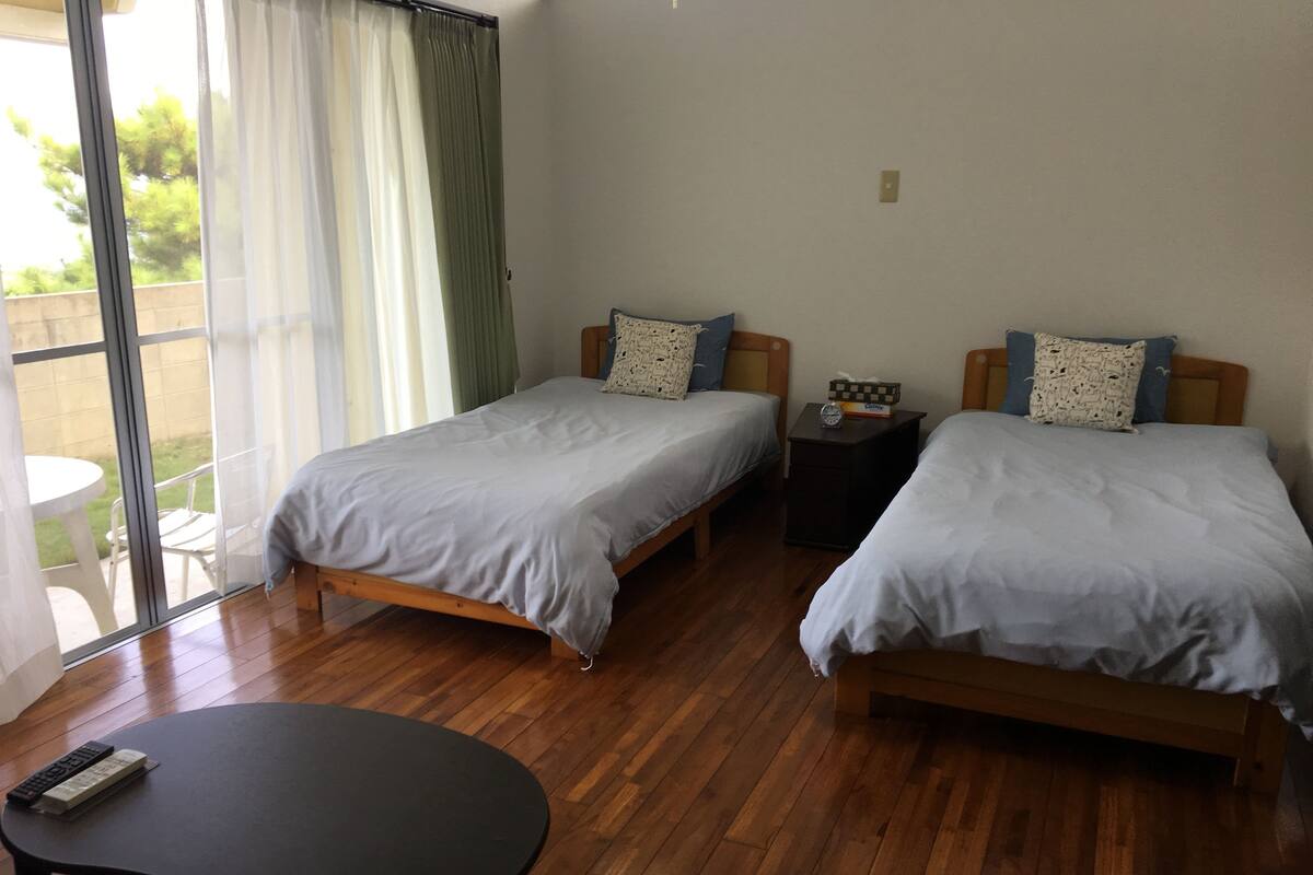 A room with two single beds, a small table, and a window with curtains.