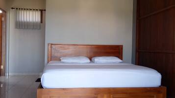 Une chambre à coucher avec un cadre de lit en bois, un matelas blanc et un ventilateur de plafond.