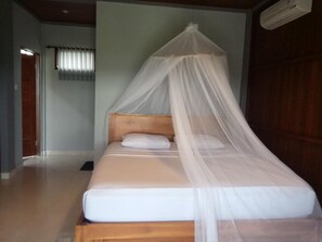 A single bed with a wooden headboard and a white mattress, covered by a white canopy. - Khalisha Villa (Mendoyo)