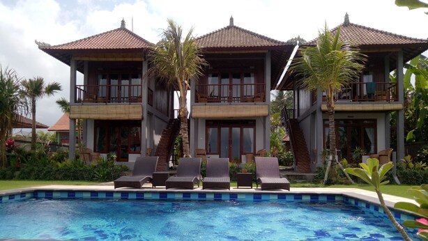 A resort with a swimming pool, lounge chairs, and a staircase leading to the upper floors. - Khalisha Villa (Mendoyo)