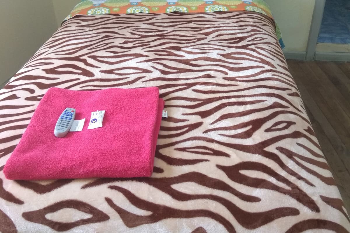 A bed with a zebra-patterned bedspread, a pink towel, and a remote control.