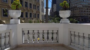 A balcony with a tiled floor and a balustrade. There are two potted plants on the balcony. - Hostal Mediodía (Quito)