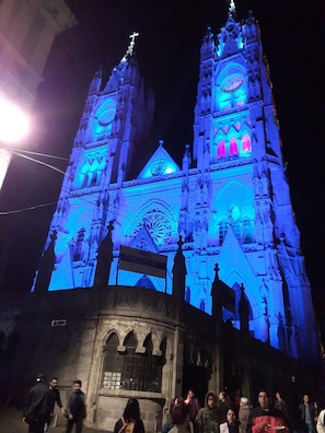 A historic building with two prominent towers, a large arched entrance, and a clock on each tower. - Hostal Mediodía (Quito)