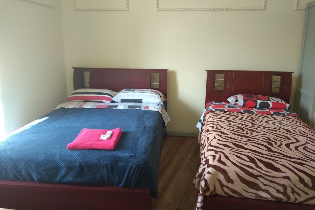 Two single beds with wooden headboards, a red blanket on the left bed, and a zebra-patterned blanket on the right bed.