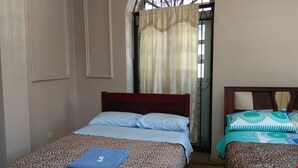 A room with two beds, one with a leopard print bedspread and the other with a geometric pattern. There is a window with a metal frame and a curtain. - Hostal Mediodía (Quito)