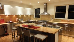 Une cuisine moderne dotée d’un îlot central, de tabourets de bar, d’appareils électroménagers en acier inoxydable et de meubles de rangement en bois.