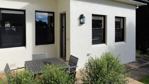 Un bâtiment moderne à l’extérieur blanc, doté de grandes fenêtres et d’un petit patio avec une table et des chaises.