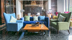 Una sala de estar moderna con un sofá azul, sillones verdes y una mesa de centro de madera.