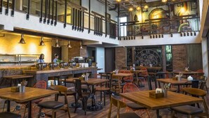 Un restaurante con varias zonas de comedor, una cocina y un entrepiso.