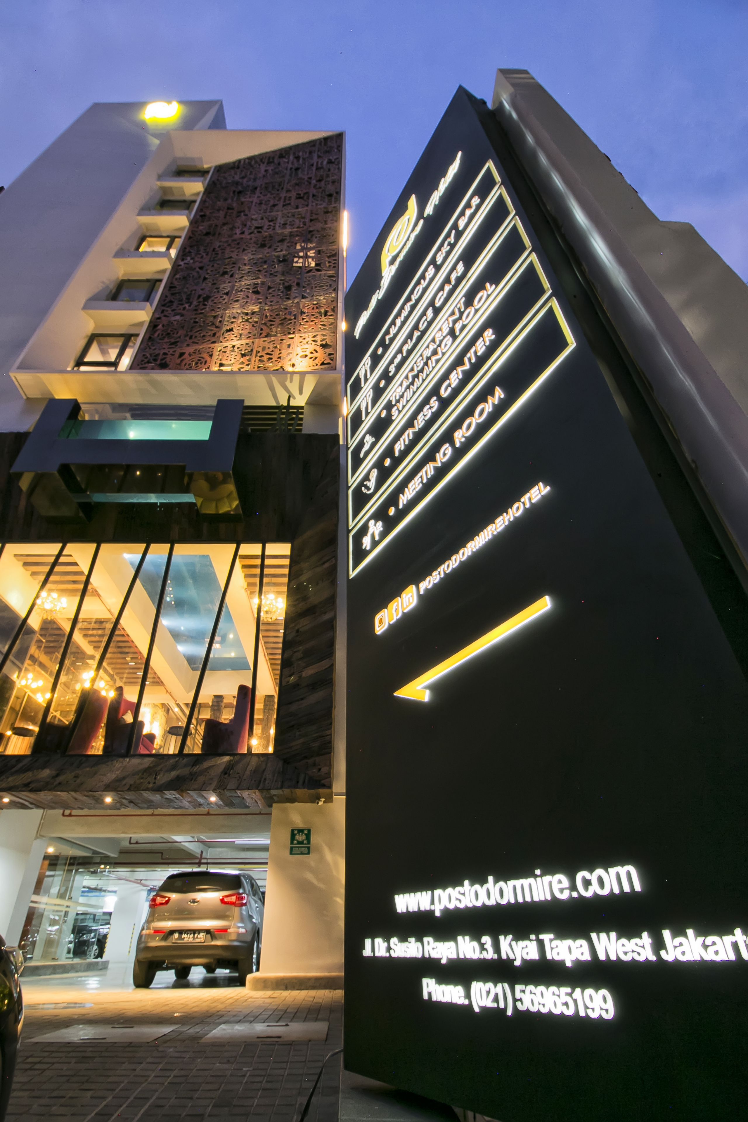 A hotel entrance with a sign indicating amenities such as a swimming pool, fitness center, and meeting room.