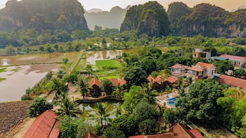 Un pueblo pintoresco a orillas del río, con casas tradicionales, una piscina y abundante vegetación.