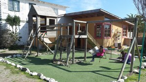 A playground with wooden structures and a swing set. - Cabañas Los Tamarugos (Los Vilos)