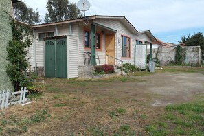 A single-story house with a front porch, a satellite dish, and a small garden area. - Cabañas Los Tamarugos (Los Vilos)