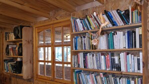 A room with wooden walls and a large bookshelf filled with books. - Cabañas Los Tamarugos (Los Vilos)