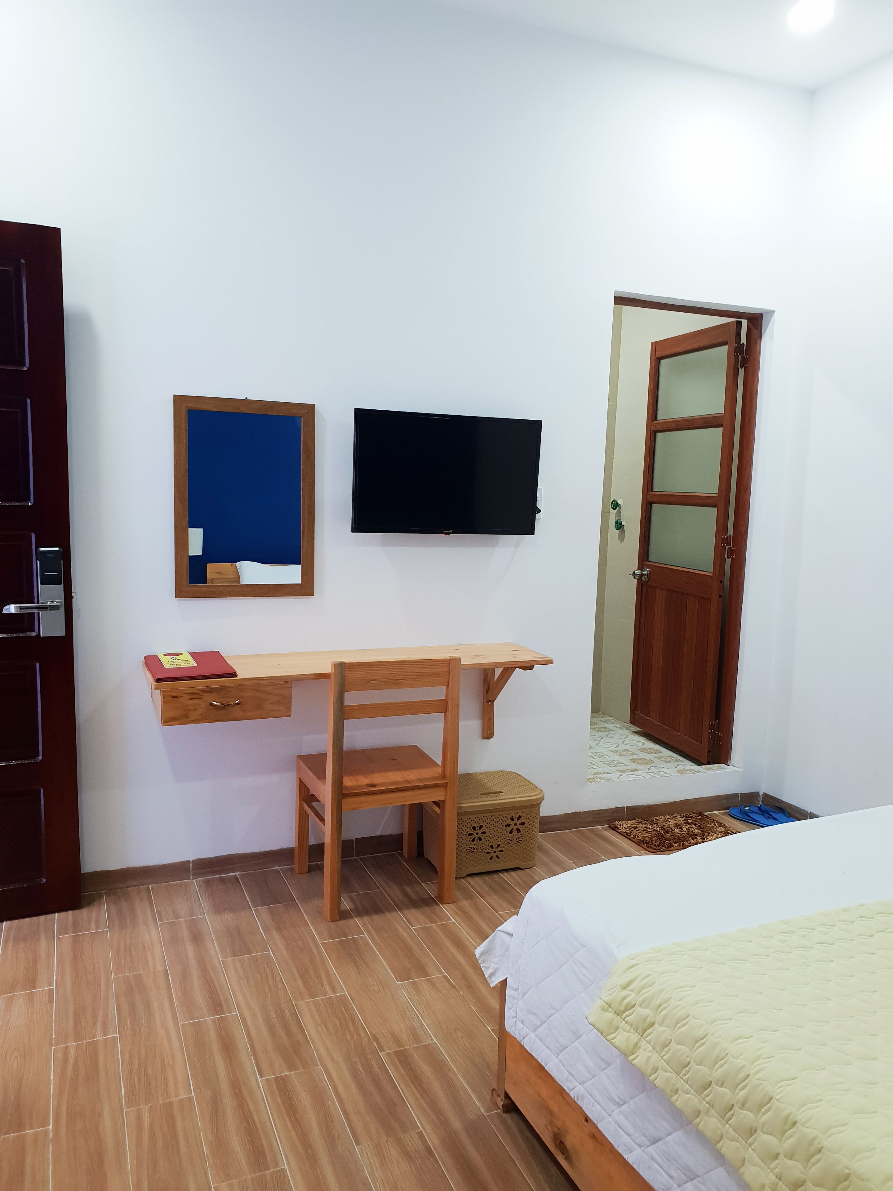 A bedroom with a wooden desk, a television, a bed, and a wardrobe.