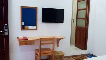 A bedroom with a wooden desk, a television, a bed, and a wardrobe.
