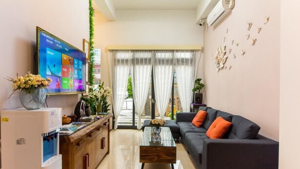 A living room with a flat-screen TV, a sofa, a coffee table, and a kitchen area with a refrigerator and a water dispenser. - Jinguann B&B (Hualien City)