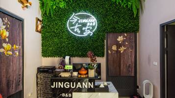 A reception desk with a neon sign, a green wall, and wooden panels.