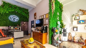 A modern hotel lobby with a green wall, a reception desk, a television, and a dining area with a table and chairs. - Jinguann B&B (Hualien City)