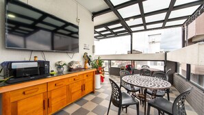 A modern kitchen with a microwave, wooden cabinets, and a large flat-screen TV. - Jinguann B&B (Hualien City)